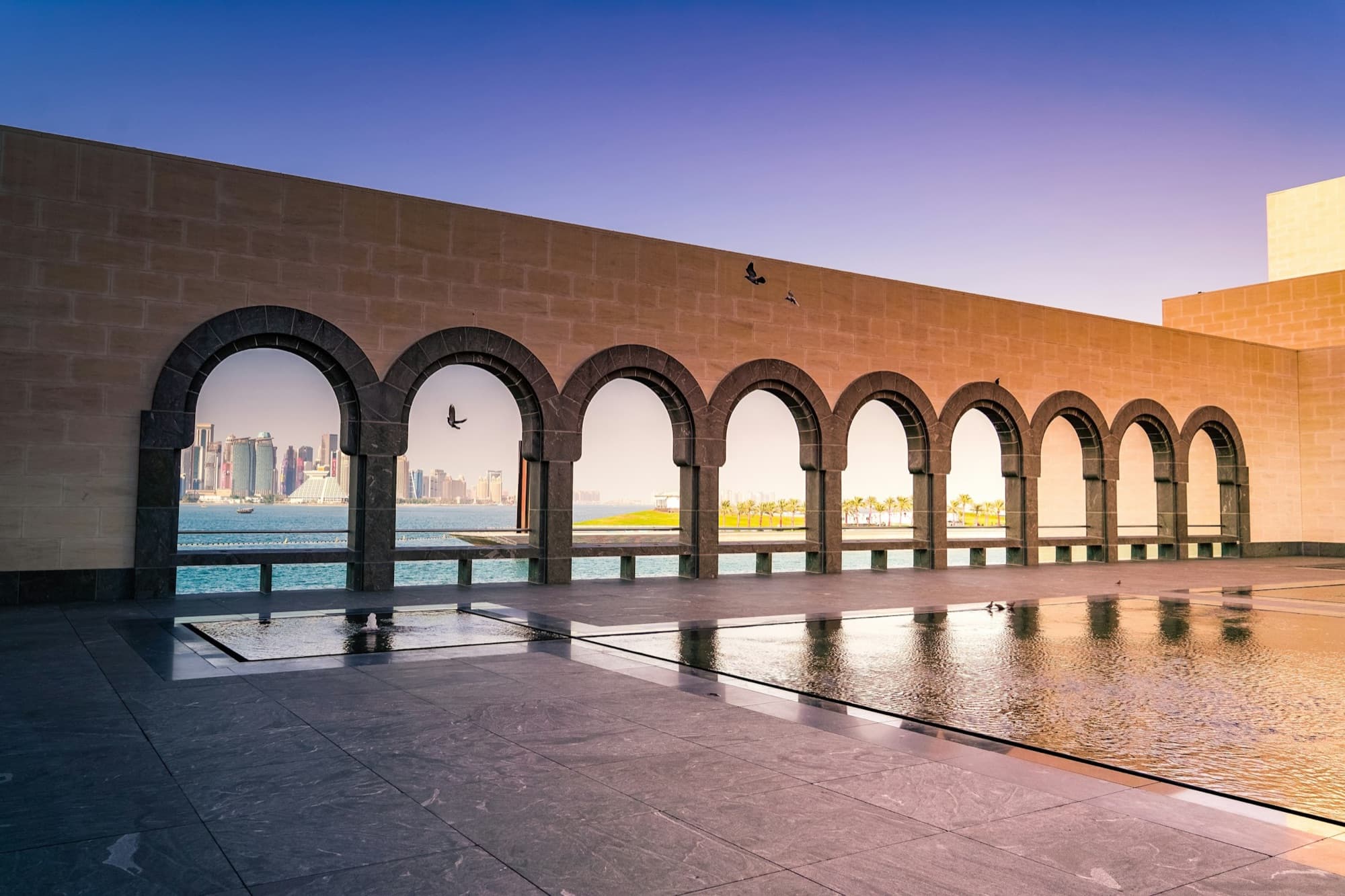 Sunlight falling through the arched stone colonnade of the Museum of Islamic Art in Doha.