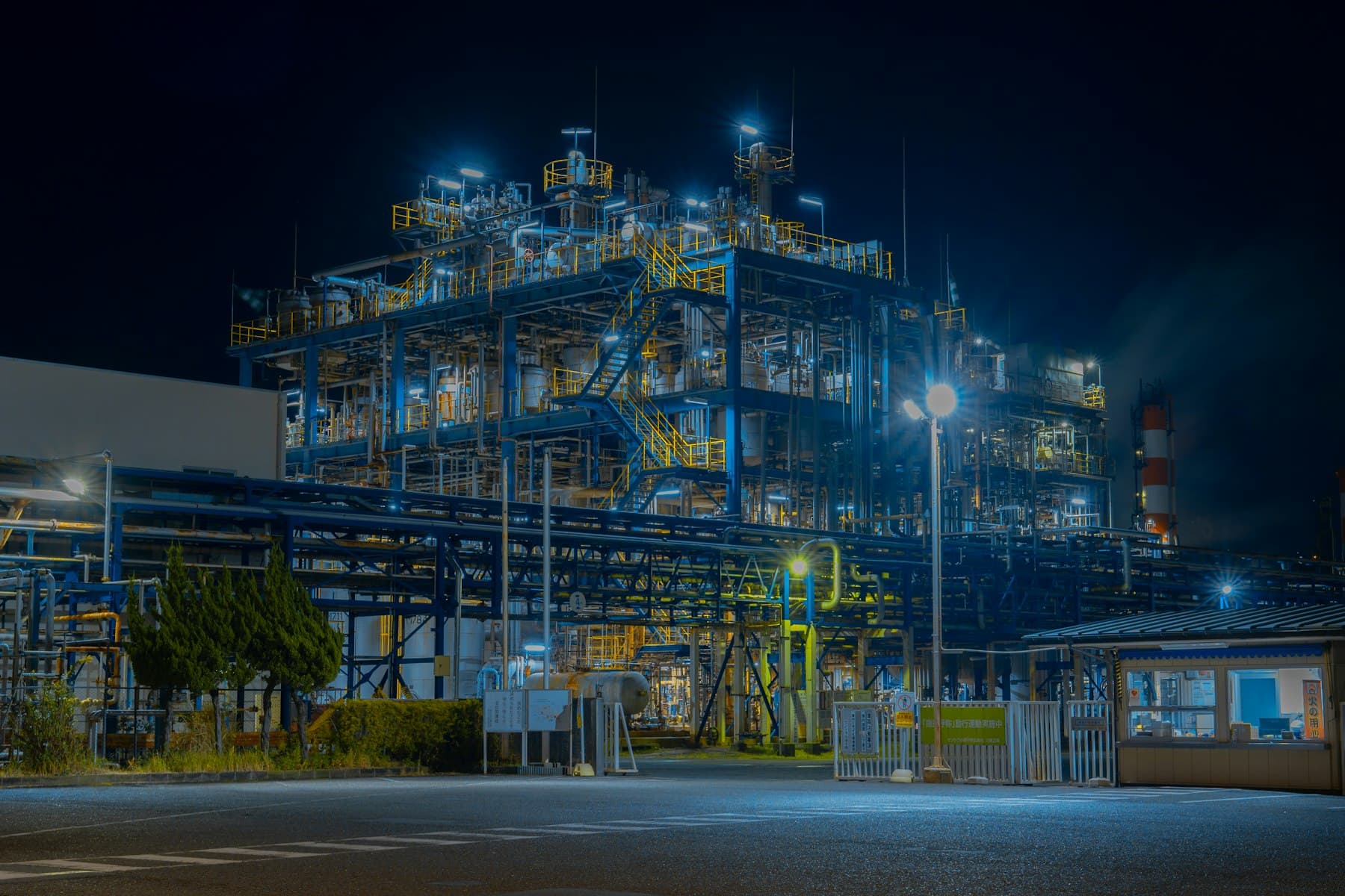 An industrial plant lit against the night sky, its towers and pipework in silhouette.