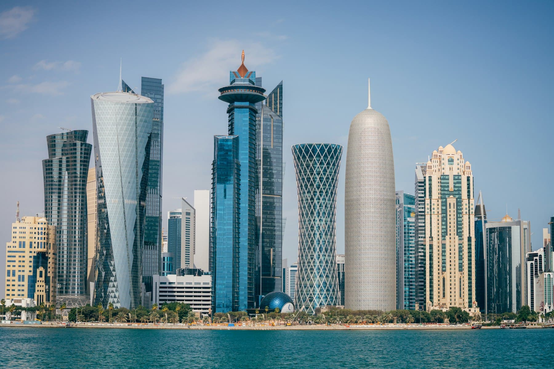 The Doha skyline of high-rise towers reflected in the waterfront at dusk.